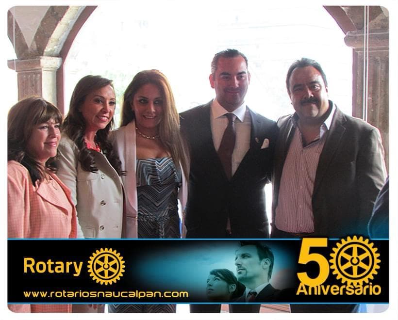 Julio Ortiz Mena posa junto a tres mujeres y un hombre bajo arcos de cantera, con la franja original «Rotary · 50 Aniversario» en la parte inferior.